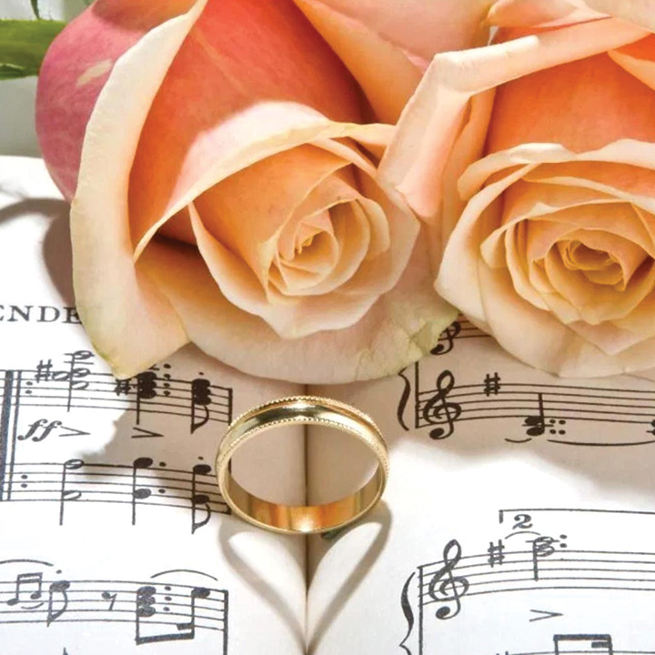 flowers and a ring on top of a sheet of music